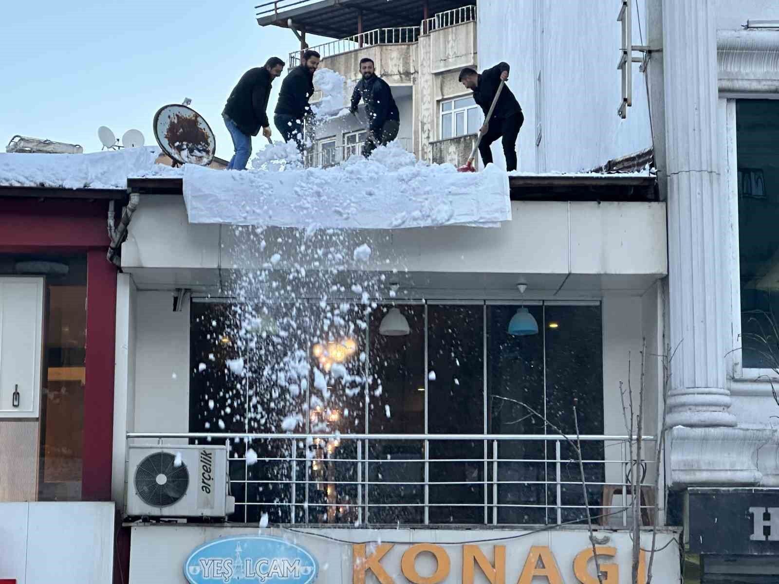 Vatandaşlar çatıdaki kar kütlelerini brandayla indirdi